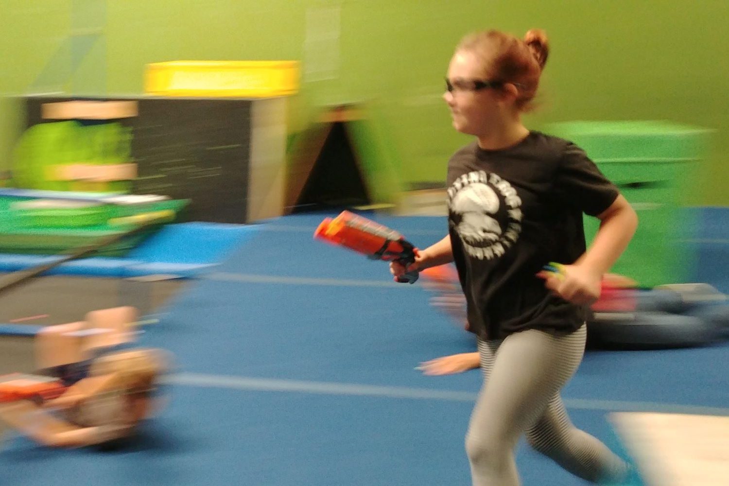 A Flying Frog day camp student running with a NERF blaster