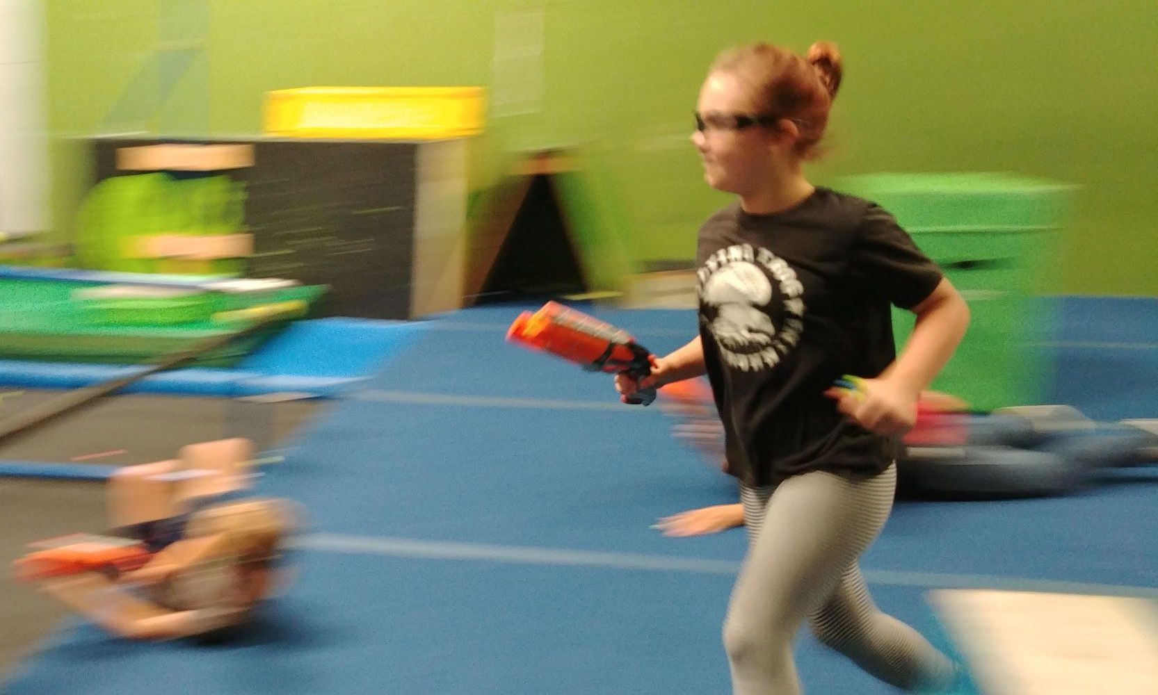 A Flying Frog day camp student running with a NERF blaster