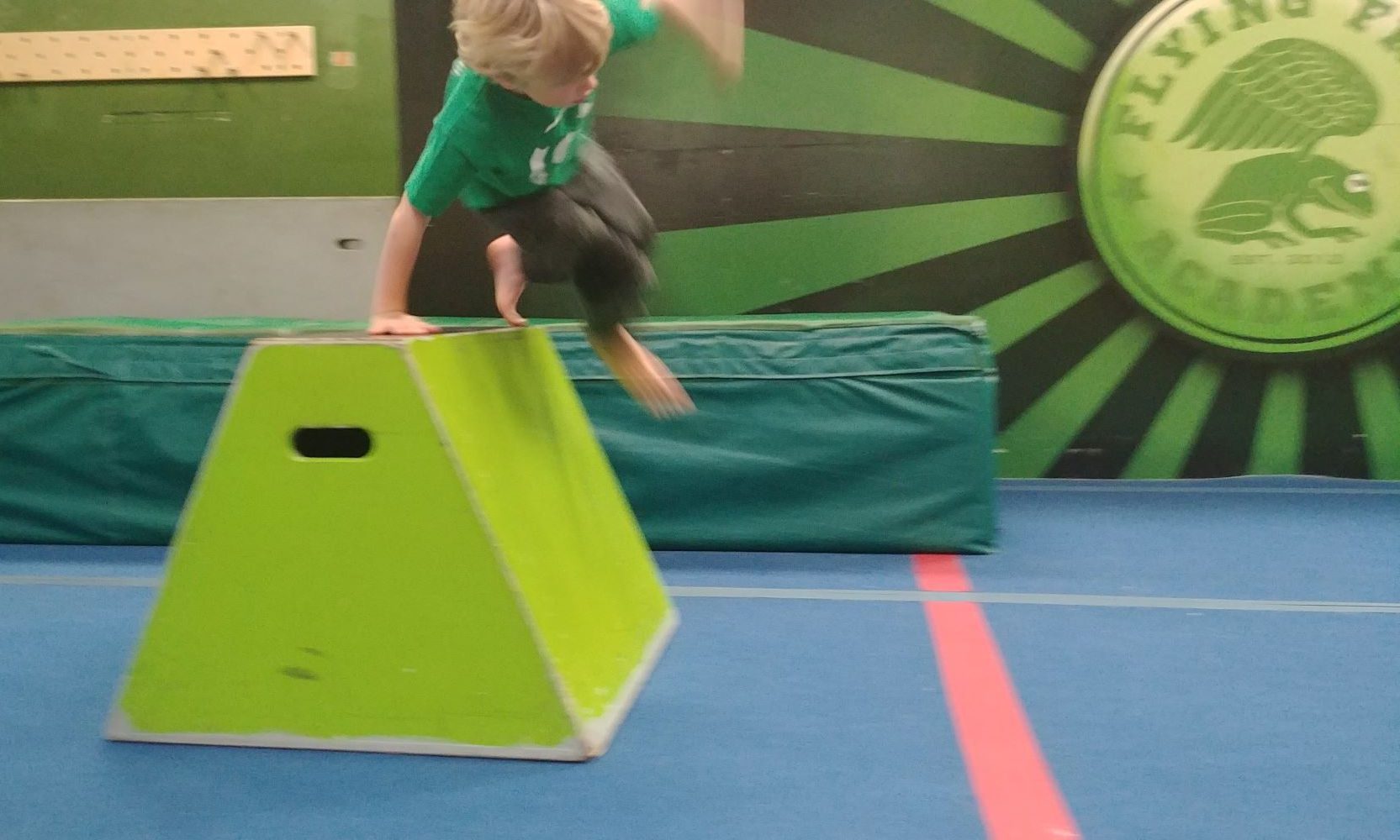 A Flying Frog student vaulting over a green block during an obstacle course at day camp